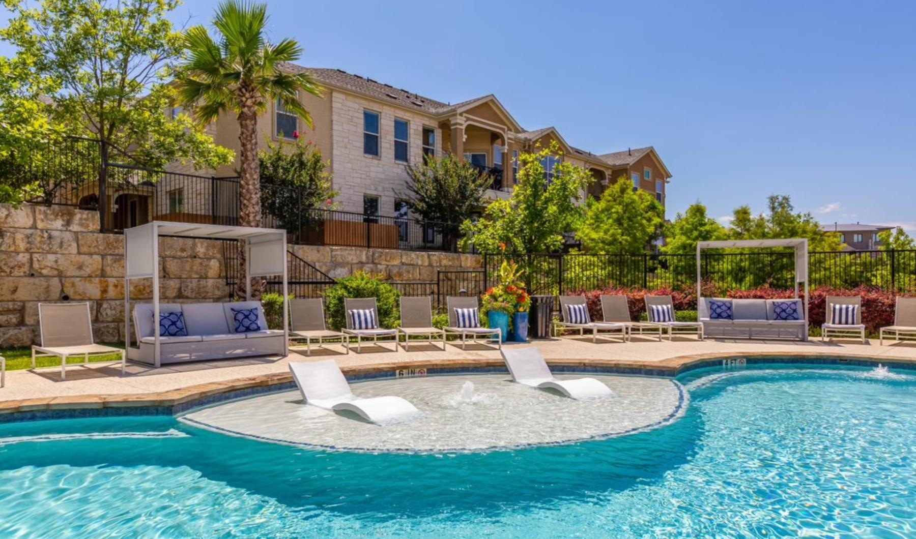 a pool with lounge chairs and a building in the background