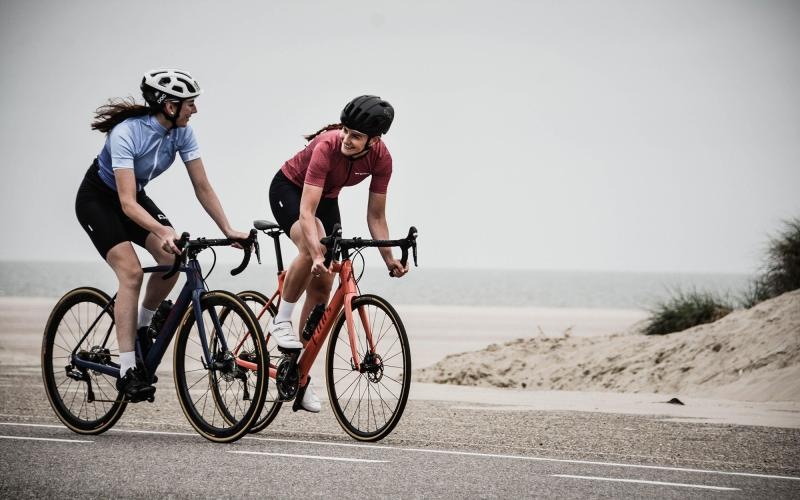 women bicycling on the road along a beach